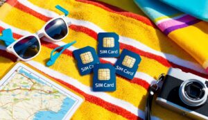 SIM cards, sunglasses, map, and camera on a beach towel